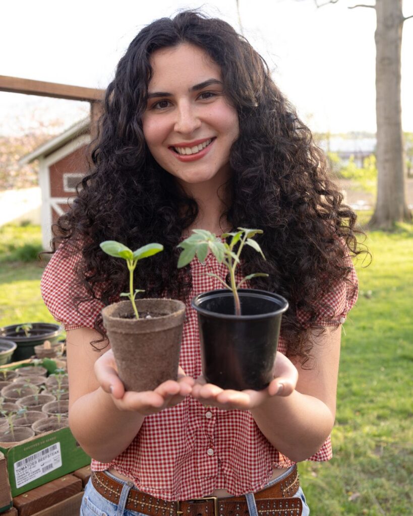 Grace holding basil and tomato plants